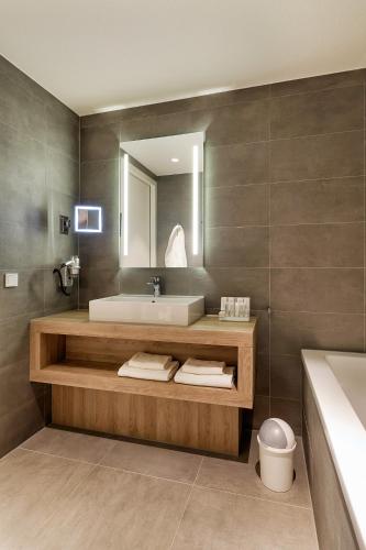 a bathroom with a sink and a tub and a mirror at Van der Valk Hotel Breda in Breda