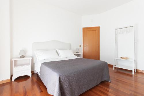a white bedroom with a bed and a wooden floor at B&B Il giardino degli incanti in SantʼElpidio a Mare