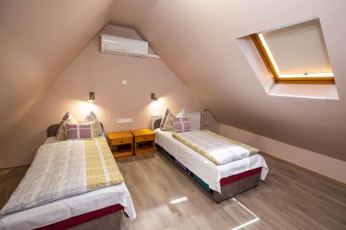 a attic bedroom with two beds and a window at Cecey Apartman in Eger