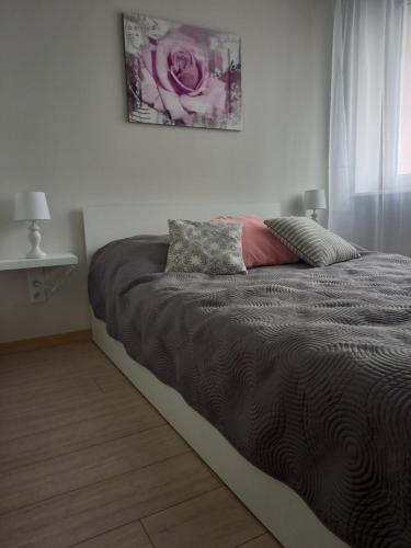 a bed in a white room with a pink rose at Apartament 26 in Drawsko Pomorskie