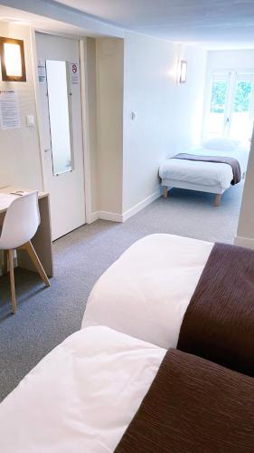 a hotel room with two beds and a desk at Abelha Hôtel Le France in Brive-la-Gaillarde