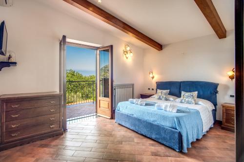 1 dormitorio con cama azul y puerta corredera de cristal en Mattia, en SantʼAgata sui Due Golfi