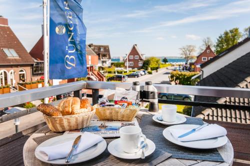 a table with plates and cups and baskets of bread at Büngers Apartment-Hotel mit Sommerstrandkorb & Gartensauna in Strande