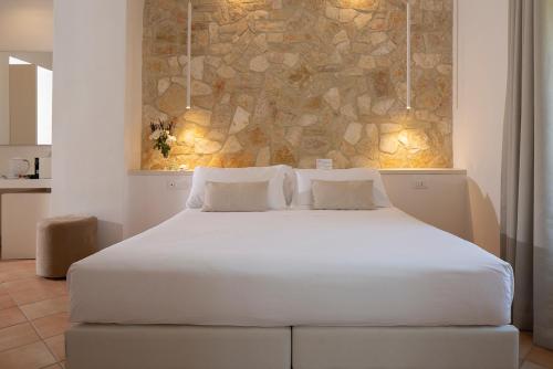 a white bed in a room with a stone wall at Giotto Country House & Spa in Assisi