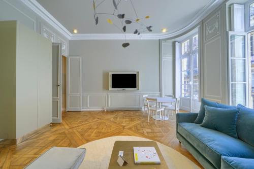 un salon avec un canapé bleu et une télévision dans l'établissement Le Paradoxe - Magnifique appartement de 80m2, à Bordeaux