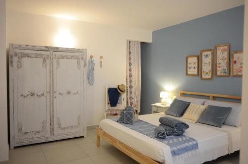 1 dormitorio con 1 cama blanca grande con almohadas azules en Villa Sangemi en Àrbatax