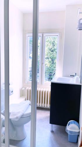a bathroom with a toilet and a sink and a window at Abelha Hôtel Le France in Brive-la-Gaillarde