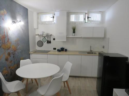 eine Küche mit einem weißen Tisch und weißen Stühlen in der Unterkunft La Piccola al Mare in Livorno