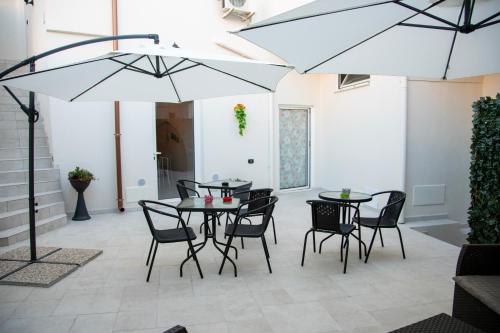 een patio met 2 tafels en stoelen en een parasol bij Dimora Guerrieri in Brindisi