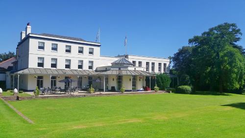 a large white building with a lawn in front of it at Mercure Thurrock Stifford Hall in Grays Thurrock