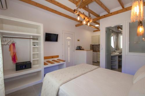 a white bedroom with a bed and a kitchen at Papafragas Studios in Pachaina