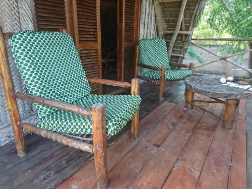 two rocking chairs and a table on a porch at COCO REEF ECOLODGE in Kizimkazi
