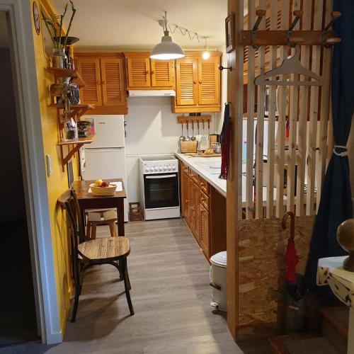 une cuisine avec des placards en bois et une table avec une chaise dans l'établissement Hier et Aujourd’hui 21, à Malakoff