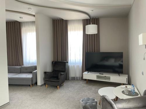 a living room with a television and a couch and a chair at Hotel Jan Sander in Aleksandrów Łódzki