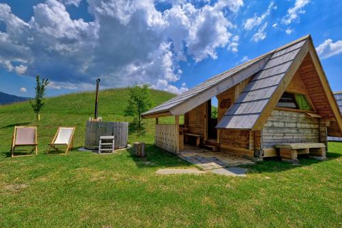 a log cabin in a field with two chairs at Glamping Brodej in Vitanje