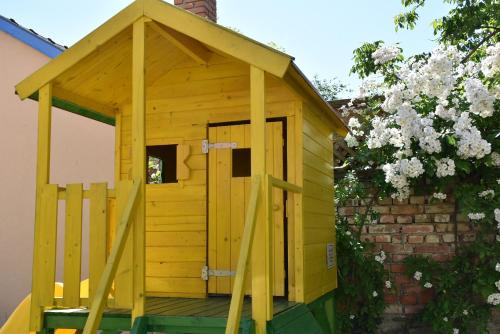 a wooden dog house with a door in a garden at Bozi Rozi Panzió in Fertőboz