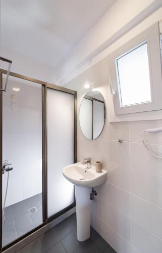 a bathroom with a sink and a shower and a mirror at Aurora Studios in Nikiana