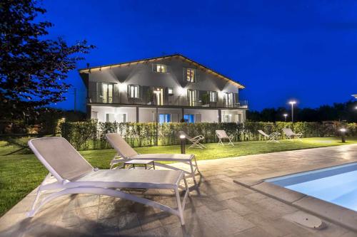 a house with chairs and a swimming pool at night at Podere Vasella - Panoramic attic in Capranica