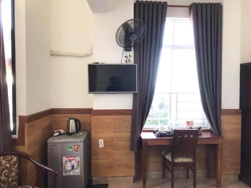 a room with a desk and a television and a window at La Cactus Hotel 2 in Quy Nhon