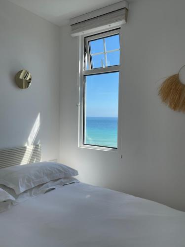 1 dormitorio con cama y ventana con vistas al océano en Harbour View House en St Ives