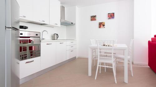 a white kitchen with a table and a white refrigerator at Italianway - Villa Tola in Valdisotto
