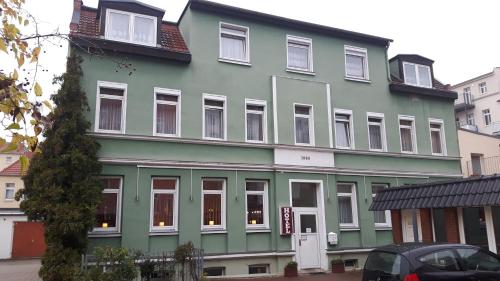 a green building with white windows on a street at Hotel & Pension Plagwitzer Hof in Leipzig
