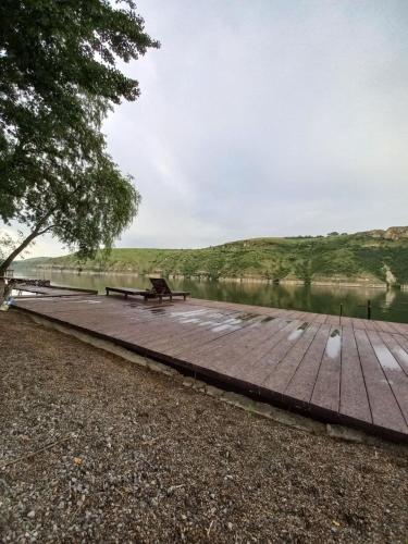 a wooden boardwalk with a bench next to a lake at Family House in Makarovka