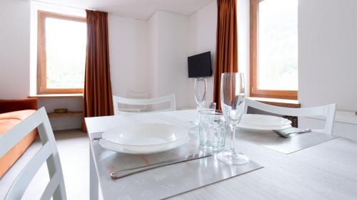 a white dining room table with glasses on it at Italianway - Villa Tola in Valdisotto