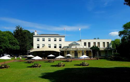 a large white building with tables and umbrellas in the grass at Mercure Thurrock Stifford Hall in Grays Thurrock
