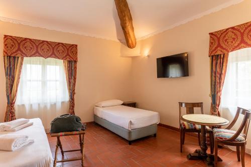 a room with two beds and a tv and a table at Hotel Villa San Michele in Lucca