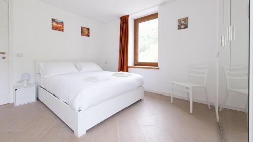 a white bedroom with a white bed and a window at Italianway - Villa Tola in Valdisotto