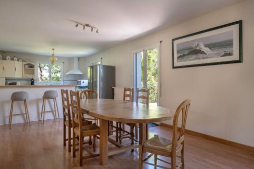 a kitchen and dining room with a wooden table and chairs at Vacances détente dans cette maison avec piscine à Crac'h in Crach