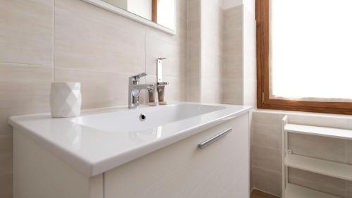 a white bathroom with a sink and a window at Italianway - Villa Tola in Valdisotto