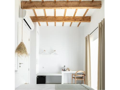a bedroom with white walls and a bed and a chair at S'Enclova Petit Hotel in Ciutadella