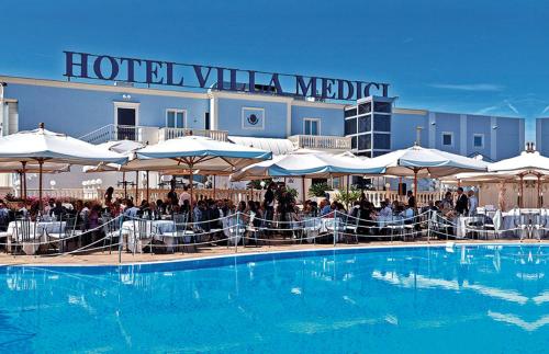 um hotel com uma grande piscina com mesas e guarda-sóis em Hotel Villa Medici em Rocca San Giovanni