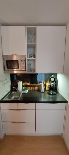 a kitchen with white cabinets and a black counter top at Appartements am Schillergarten in Dresden