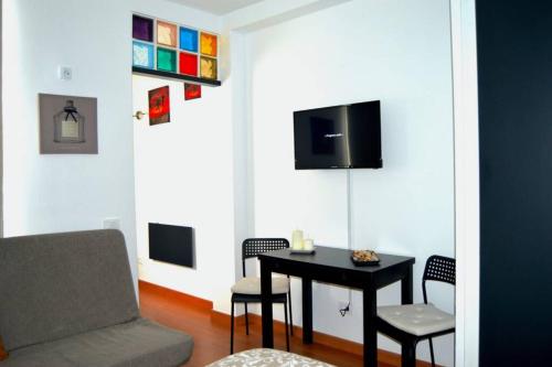 a living room with a table and chairs and a tv at Comfy Box Las Canteras in Las Palmas de Gran Canaria
