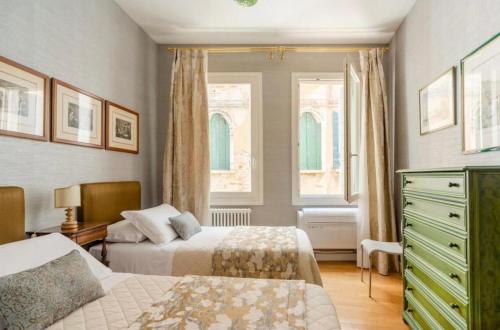 een slaapkamer met 2 bedden, een dressoir en 2 ramen bij Venezia San Samuele in Venetië