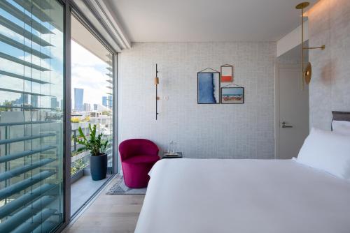 ein Schlafzimmer mit einem großen Bett und einem roten Stuhl in der Unterkunft Ink Hotel in Tel Aviv