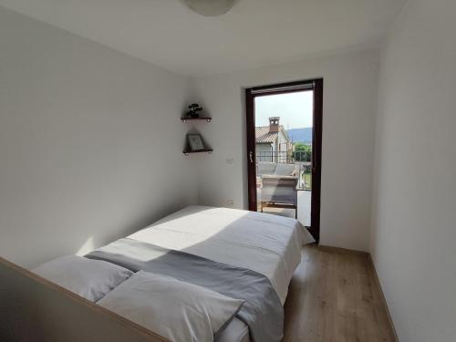 a white bedroom with a bed and a window at Bellevue in Marezige