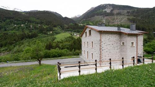 a building on a hill next to a road at Italianway - Villa Tola in Valdisotto