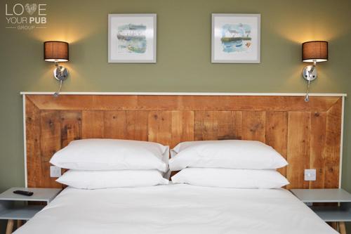 uma cama com almofadas brancas e duas luzes na parede em rooms@73 em Waterlooville