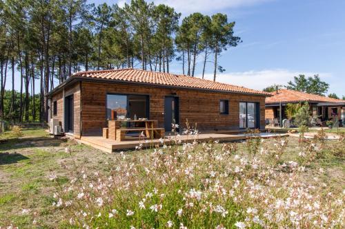 een klein houten huis in een bloemenveld bij Maison Gemme a Landes in Léon