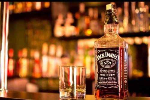 a bottle of whiskey sitting next to a glass at Ely's Mansion-24h Check-in in Bucharest
