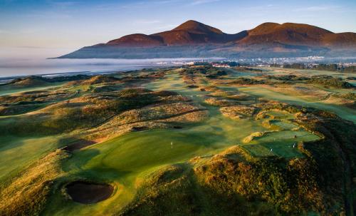 an aerial view of a golf course with mountains in the background at 3 Post Office Lane 4 Star Tourism NI accommadation in Newcastle
