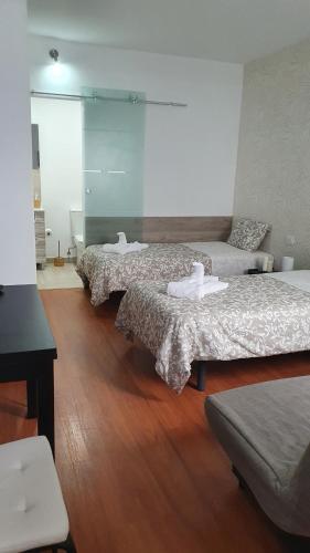 3 camas en una habitación con suelo de madera en Comfy Box Las Canteras, en Las Palmas de Gran Canaria