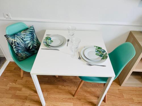 uma mesa branca e cadeiras com pratos e copos em LE COSY - Lumineux - Proche de Rennes - Spacieux em Liffré