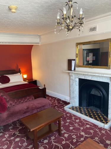 um quarto de hotel com uma cama e uma lareira em The Tudor Hotel em Bridgwater