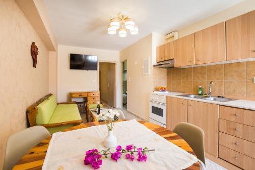 a kitchen and dining room with a table with flowers on it at Limonero New City Apartment 1 with Private Parking in Lefkada