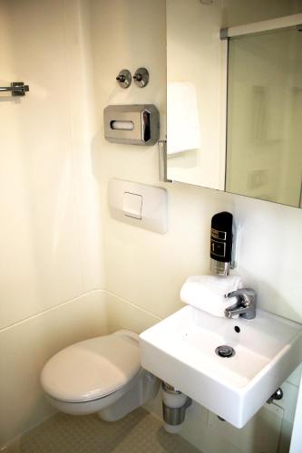 a bathroom with a white toilet and a sink at bestprice Hotel Bendorf Koblenz in Bendorf